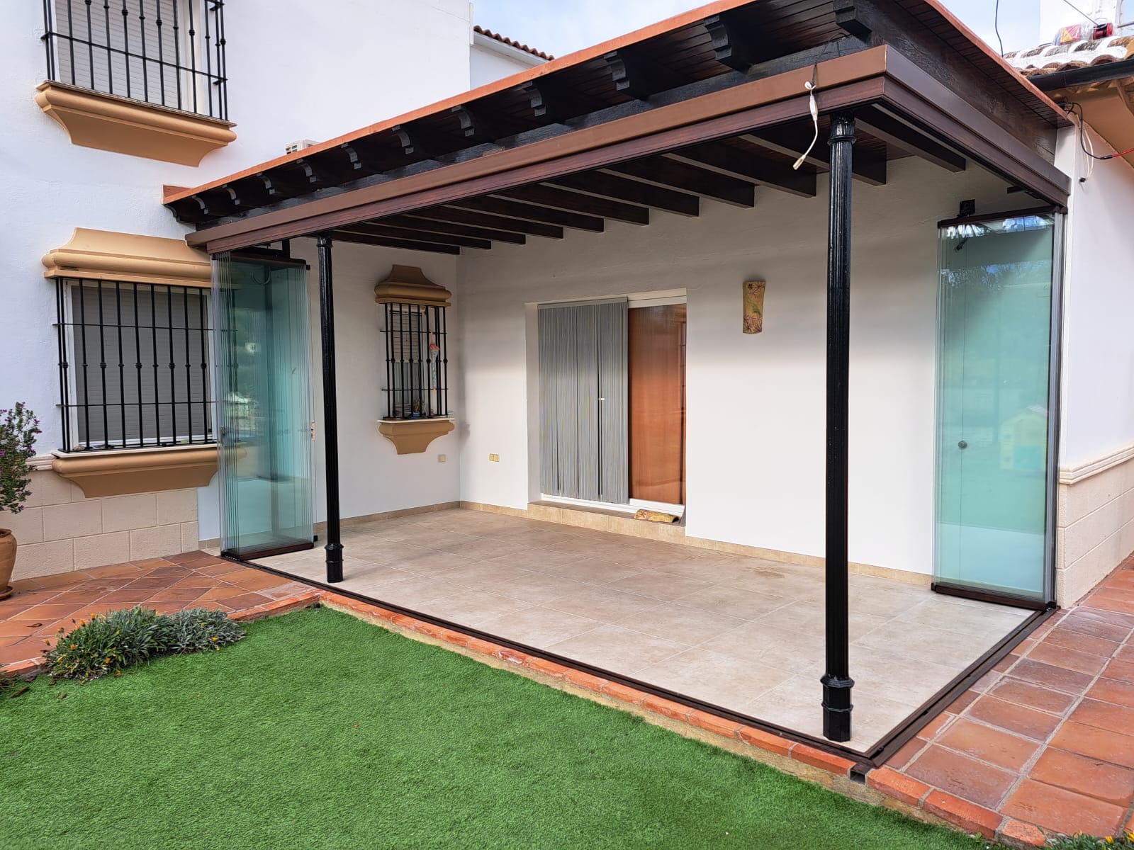 Cerramiento elegante de terraza con perfiles de PVC blanco, proporcionando aislamiento acústico y térmico